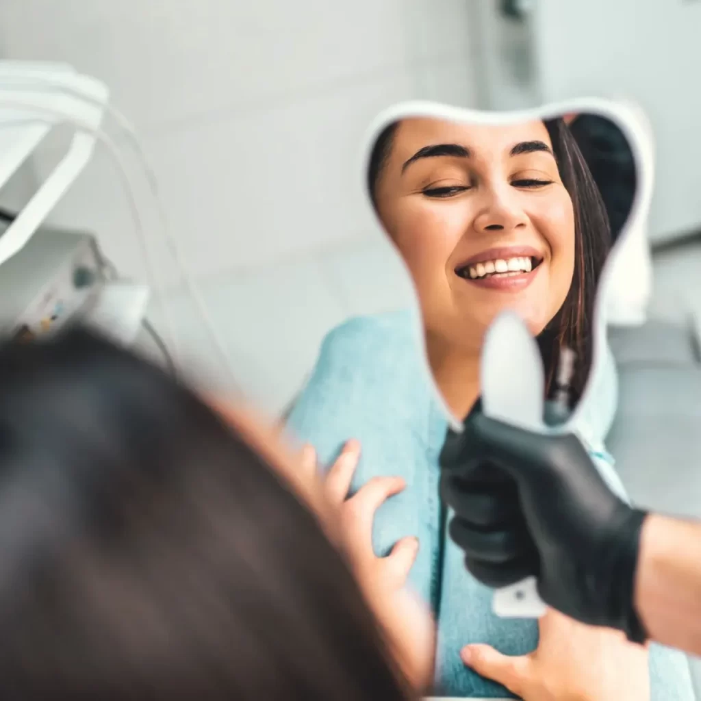 Jovem mulher sorridente vista a partir do espelho da Dentista.